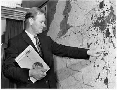 T Dan Smith Archive: Mr T Dan Smith, chairman of the Northern Economic Planning Council, with his personal copy of 'Challenge of hte Changing North' studying a giant wall map of the Northern Region in his office, 1966