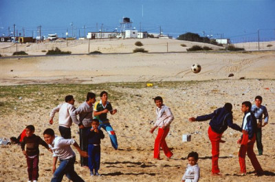 Gaza Strip: Palestinian youths play football outside Israeli fortified settlement, 1987/1988