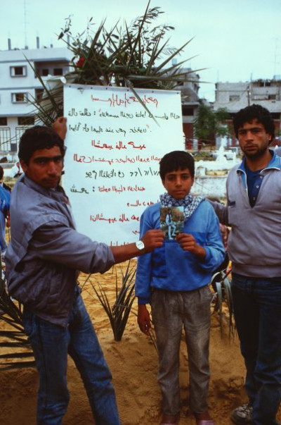 Gaza Strip: Brothers show photo of their brother shot by Israeli soldiers – Jebaliya camp graveyard, 1987/1988
